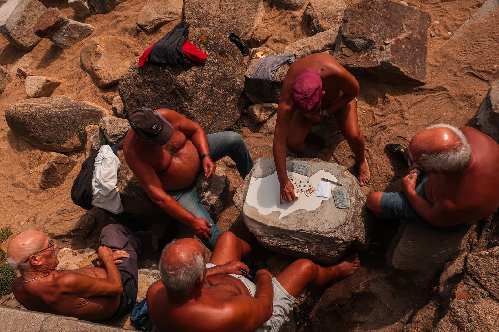 Captured in Porto, Portugal (2023): a group of elder men enjoying a game of cards in the warm sand.